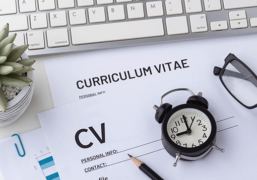 Un curriculum vitae con una sveglia e una tastiera. Rappresenta l'andamento corrente del mercato del lavoro italiano.